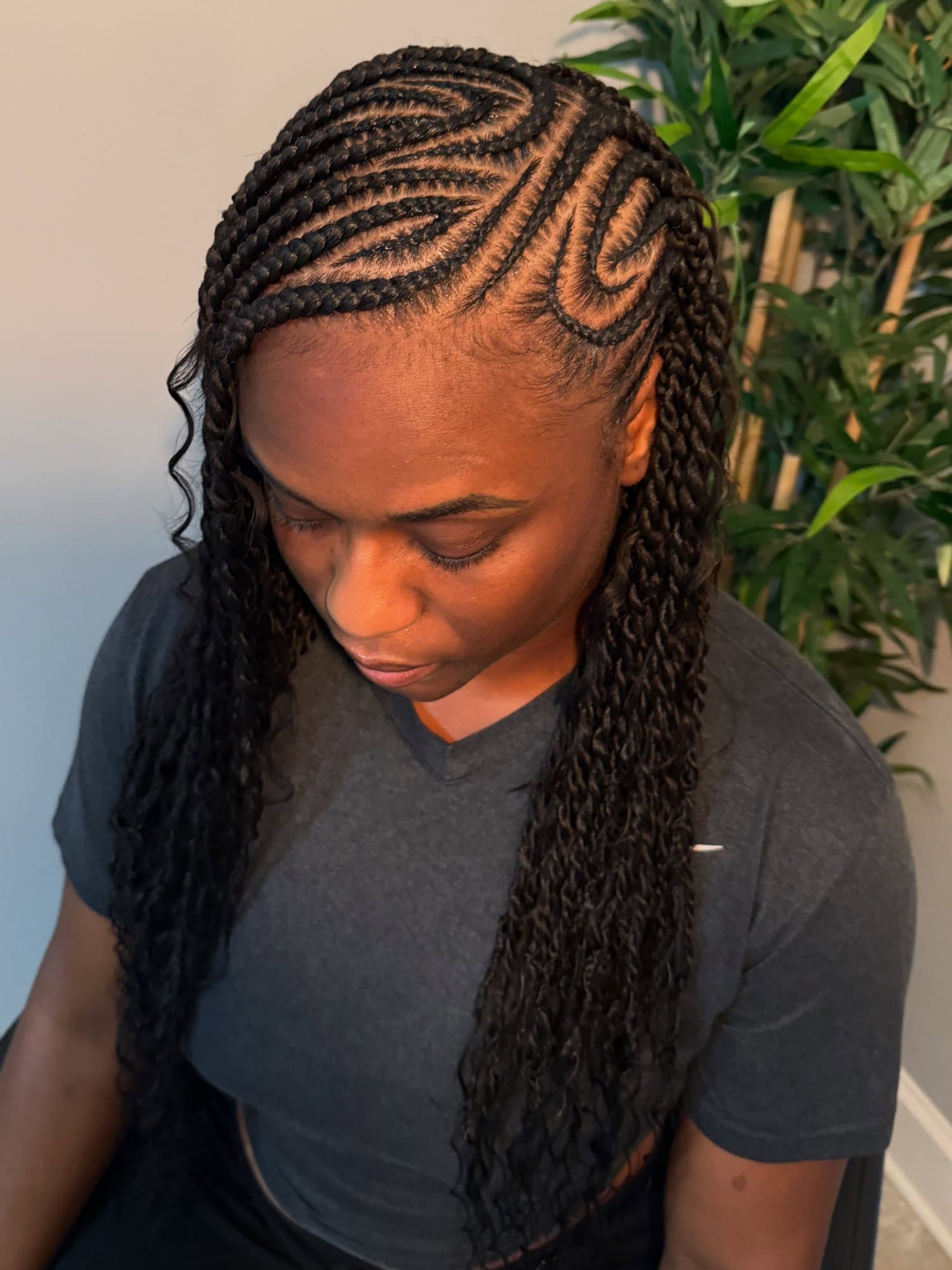 Fulani cornrows with a curved swirl parting at the front and boho twists falling long down one side