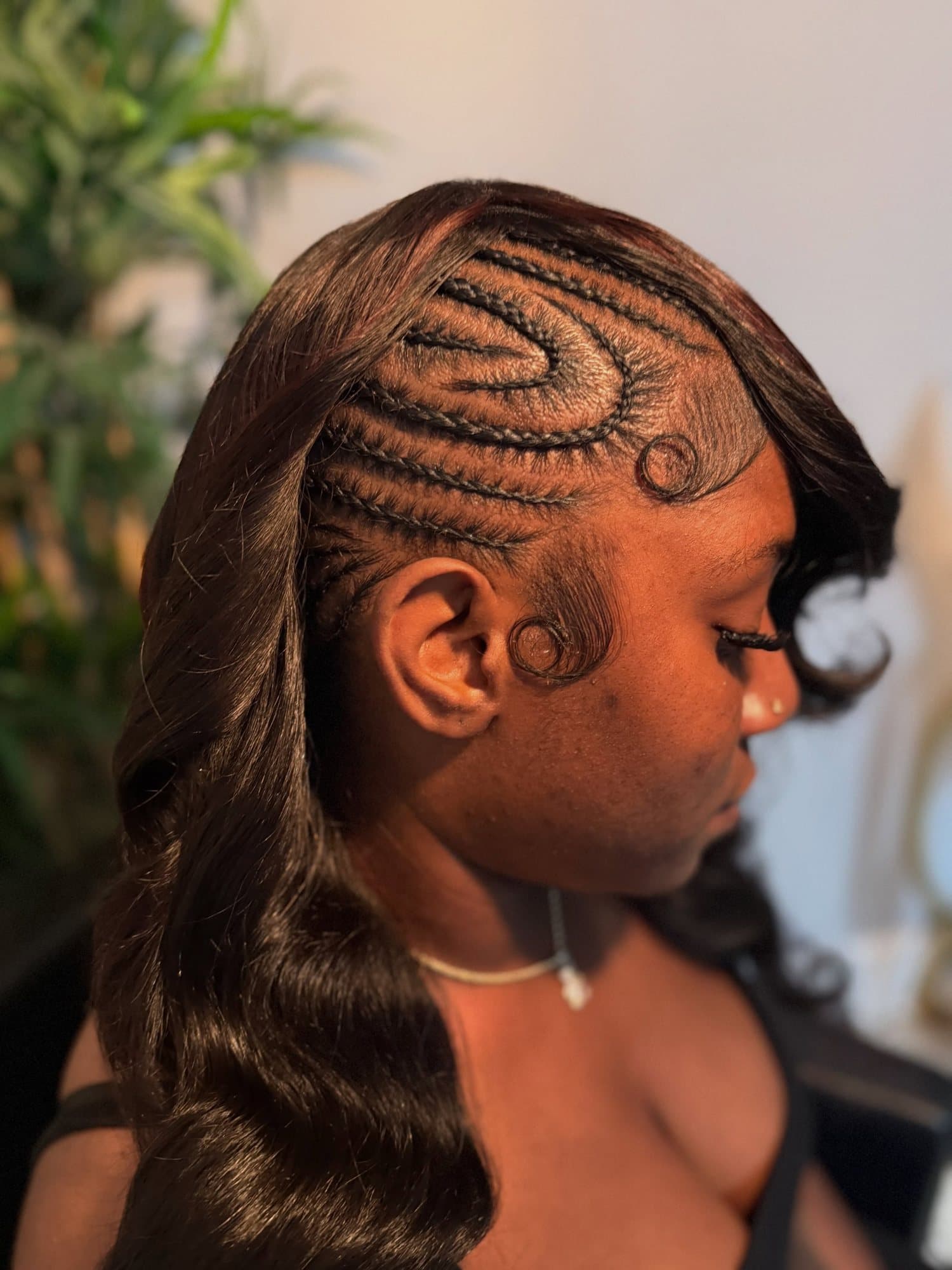 Side profile showing intricate swirled cornrow linework at the temple, each parting cut clean against the scalp